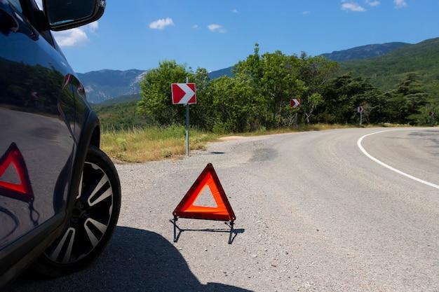 At what distance should the warning triangle be placed if a vehicle breaks down outside city limits? 